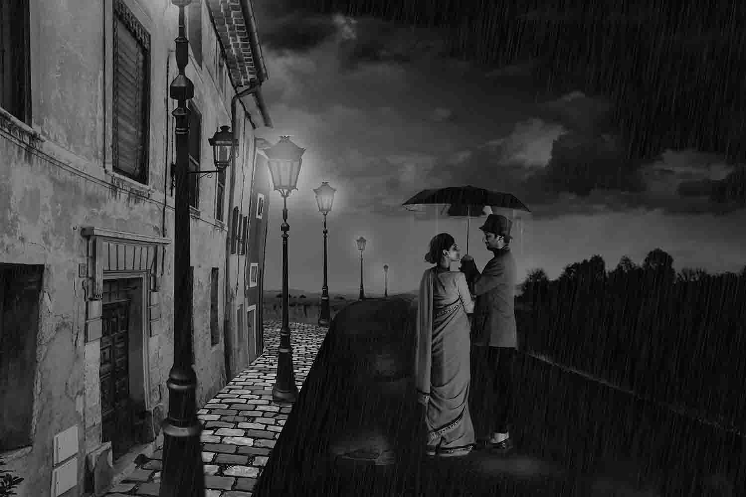 A black-and-white composite of a couple sharing an umbrella in the rain on a lamp-lit cobbled street, the woman in a sari and the man in a hat.
